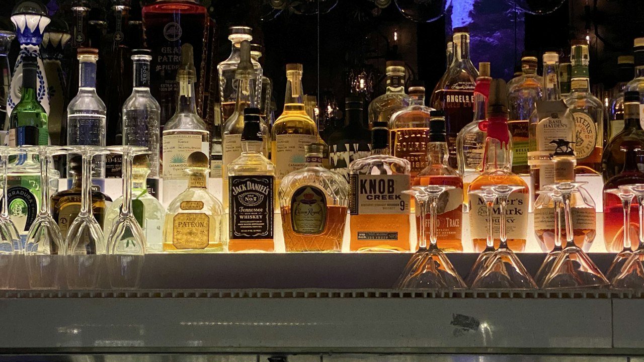 Backlit shelf of whisky and spirit bottles in warm golden light